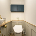 框デザインの腰壁や収納扉、ヘリボーン柄の床がレトロ感を出しているトイレ